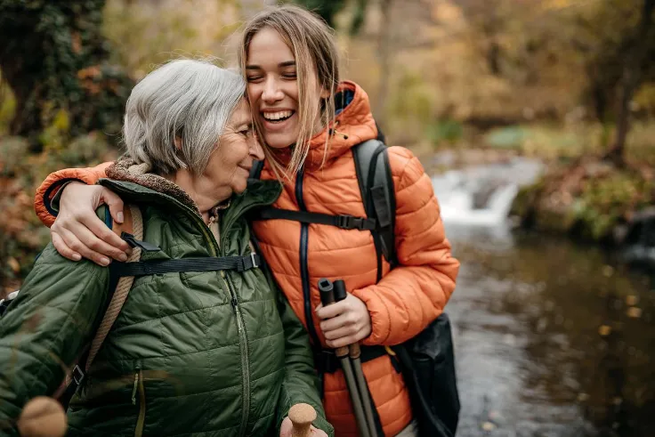 Retired women and her granddaughter hiking on mountain, walking through forest